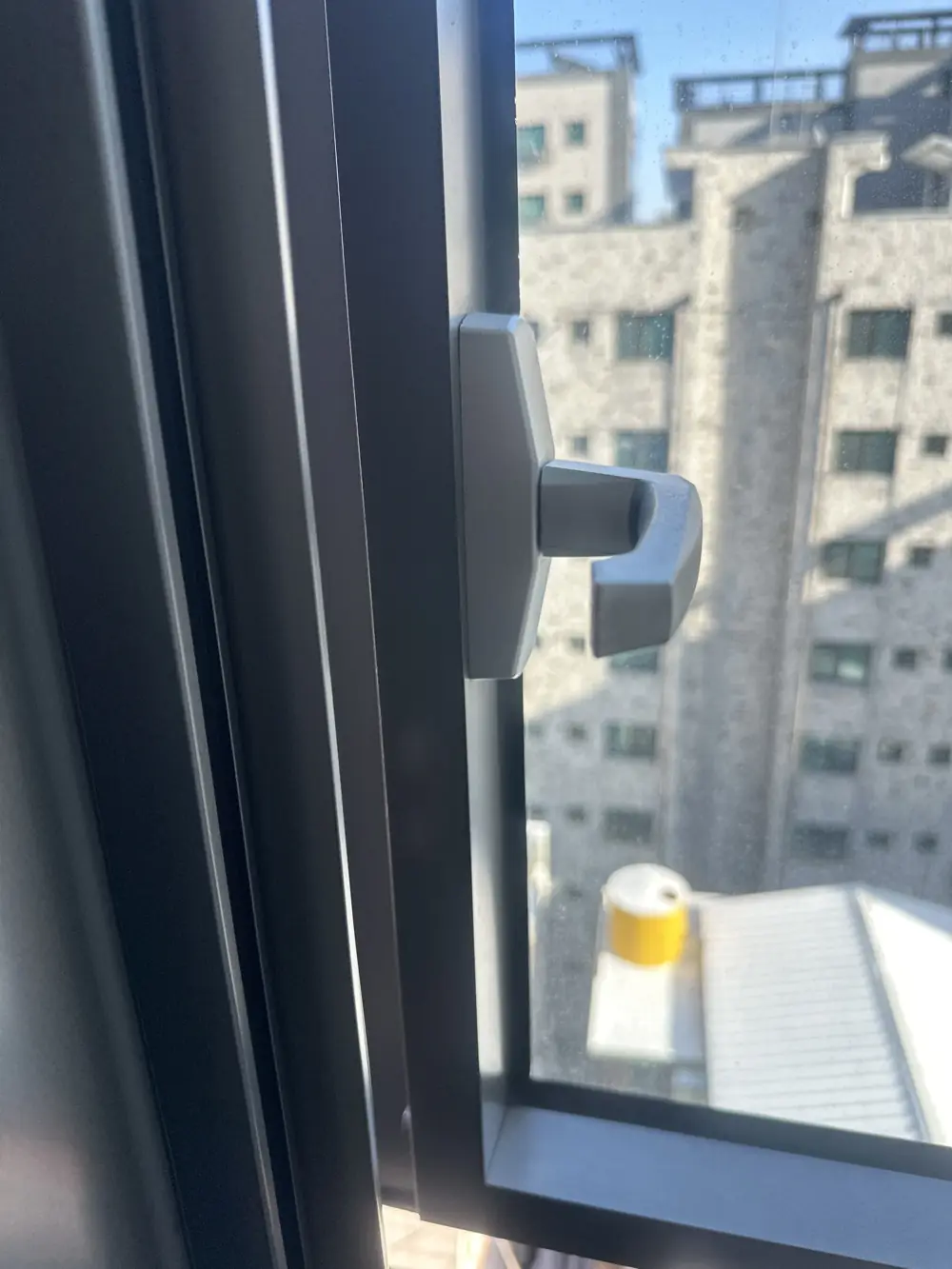 고장으로 안 열리던 짧은 갈고리형 손잡이가 달린 어두운 프레임 창 이전